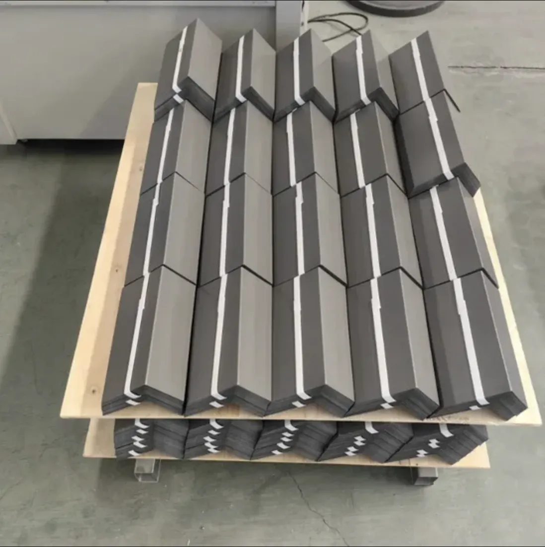 Stacked galvanized counterflashing-style formed parts on pallets in the shop