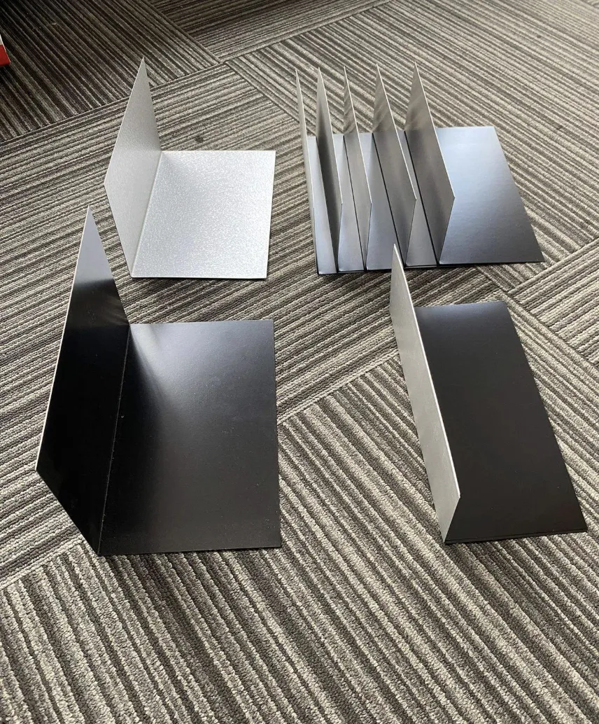 Brake-formed wall ledger and roof-to-wall flashing samples arranged on a floor for review